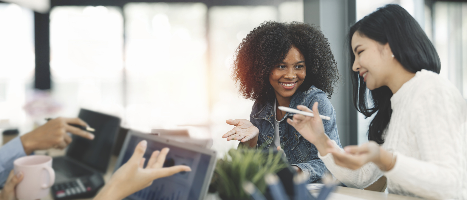 two young business professionals work on a project, smiling at one another. The Valley List offers Website design in Charleston