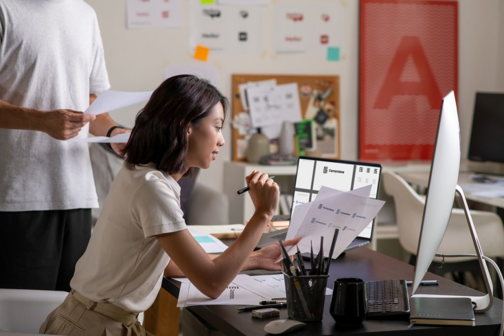 A woman sits at a computer working on a web design project. The average time spent on a website is crucial to your website success.