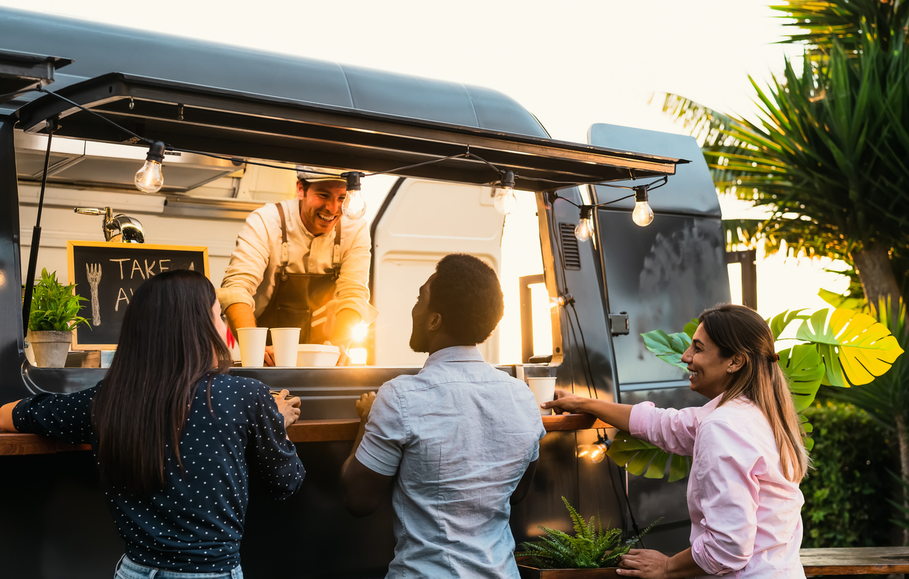 A group of friends order food from a food truck, the owner is smiling. It is evening. The Valley List is the answer to all your web development in Cambridge, as well as web development Ohio needs.