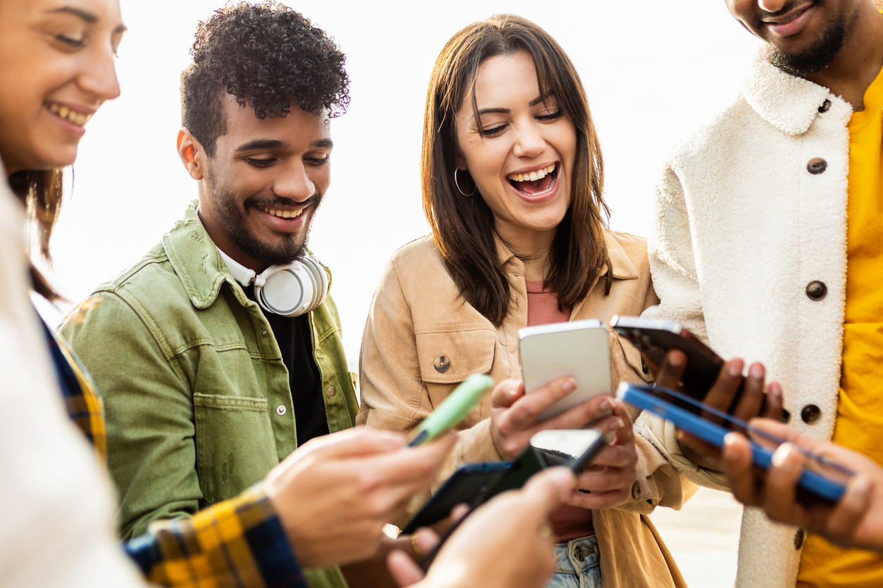 A group of young friends use their smartphones and laugh. The Valley List is a trusted website design company in Huntington.