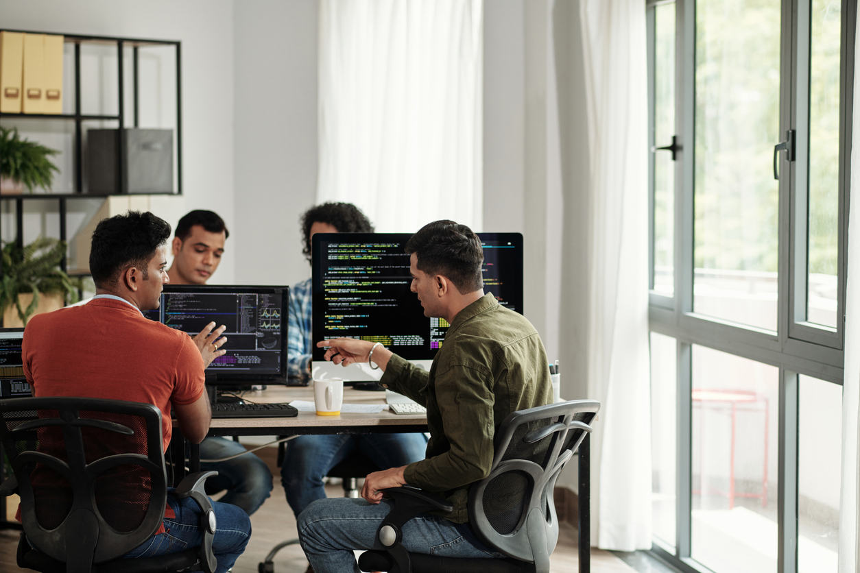 Four men sit around three computers, working on website maintenance. The Valley List offers website maintenance in Columbus, OH