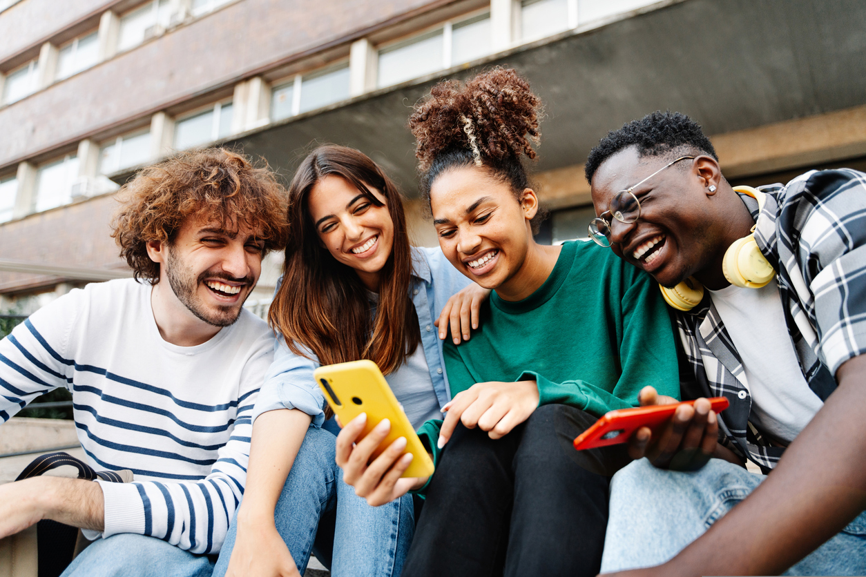 Group of university student friends sitting together using mobile phones to share content on social media. Digital marketing strategies are simple, with the right tools from The Valley List.