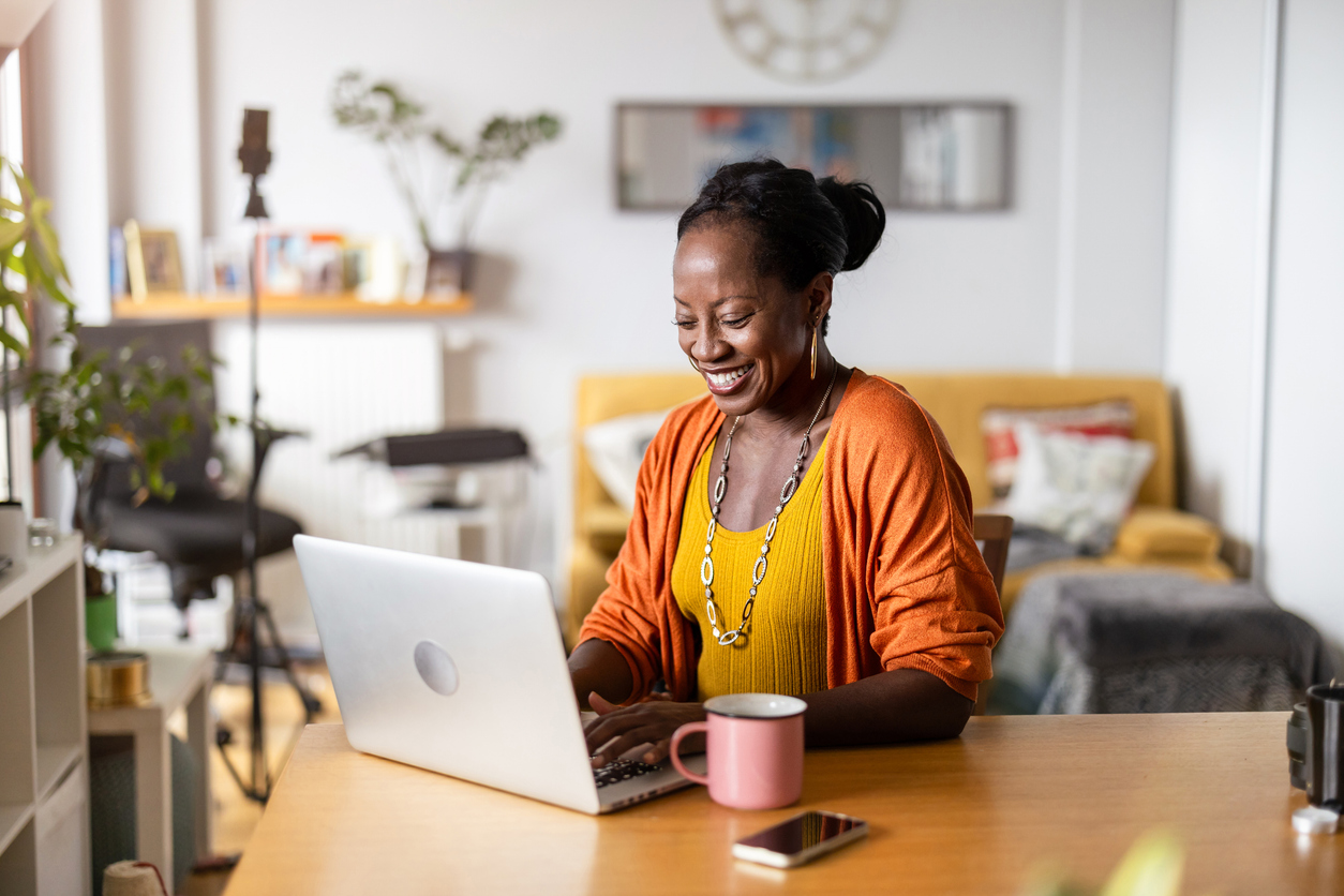 A woman works at her home business, with her laptop and a cup of coffee on the table. She is smiling. The Valley List is here to help with your website maintenance in Westerville, Ohio needs.