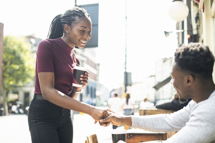 A woman in business attire shakes hands with a young man who is sitting outside of a cafe. The Valley List is a website design company in Bexley, Ohio