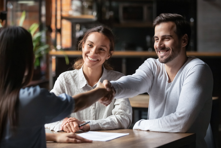 Two people shake hands across the table, as a smiling woman sits at the desk with them. The Valley List is a trusted white label agency in Bexley, Ohio.