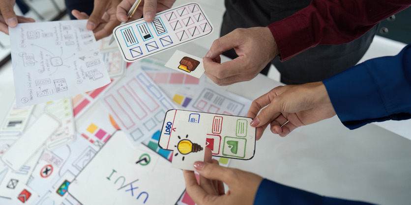 An up-close photo of folks with a printed out version of a wireframe for a mobile app. As a website redesign agency, we enjoy helping websites get a complete refresh.