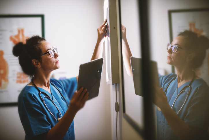 A nurse smiles as she holds up a tablet and writes information down on a wall. The Valley List offers professional web development in Olmos Park, Texas.