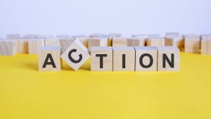 The word "action" is spelled out in wooden blocks. This article discusses the importance of good actionable buttons, that people will actually follow.